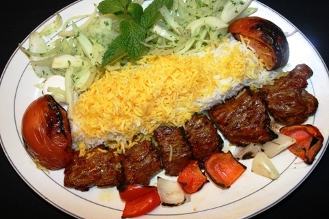 a white plate topped with meat and veggies covered in cheese next to other foods