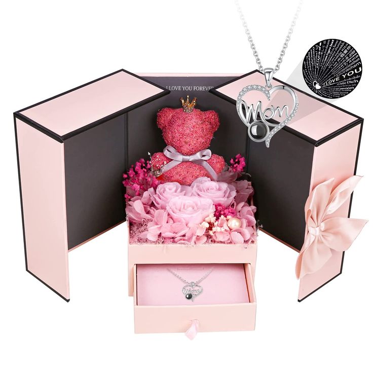 an open pink box with a teddy bear in it and flowers on the bottom shelf