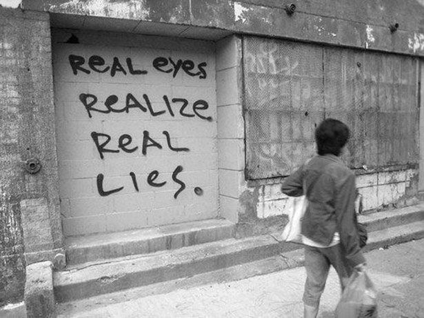 a young boy walking down the street with a bag in his hand and graffiti on the wall behind him