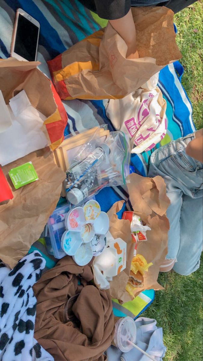 a person laying on the grass with some items in their hands and clothes around them