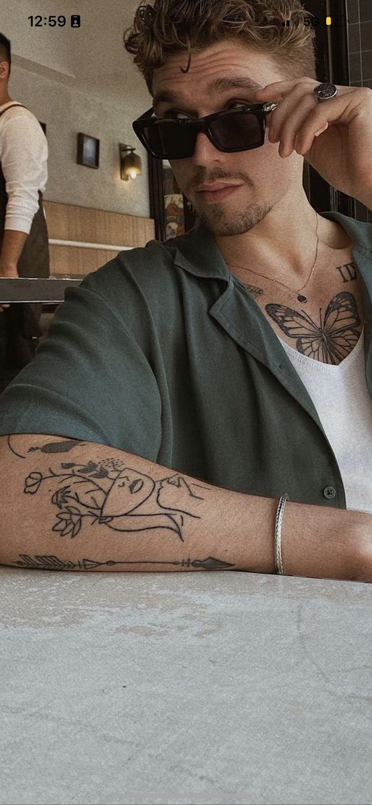 a man sitting at a table with tattoos on his arm