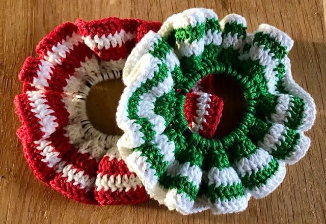 two crocheted christmas wreaths sitting on top of a wooden table