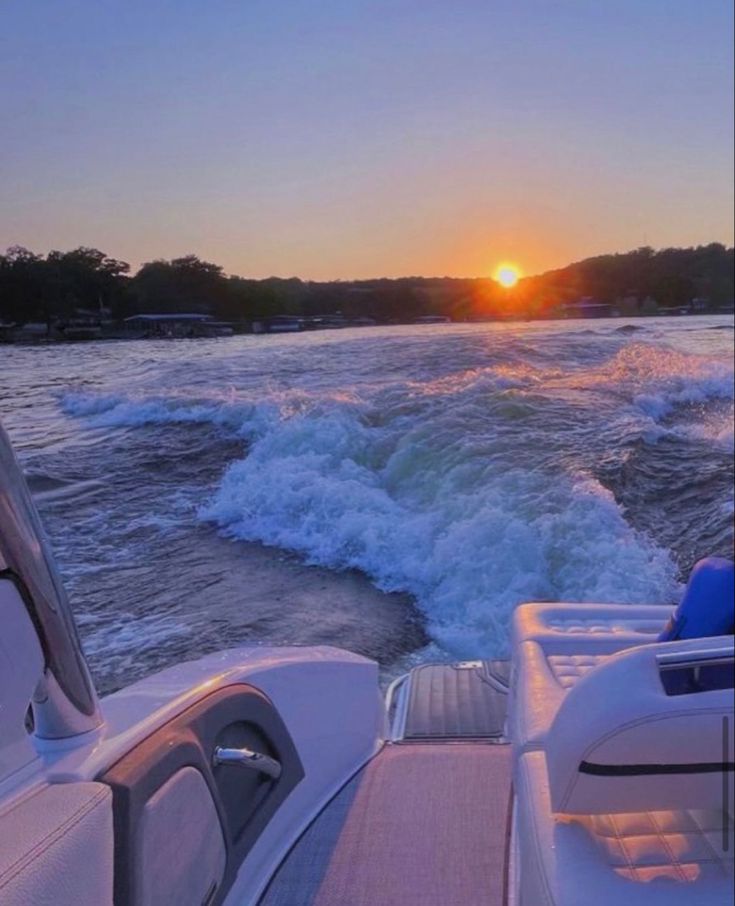 the sun is setting over the water on a boat