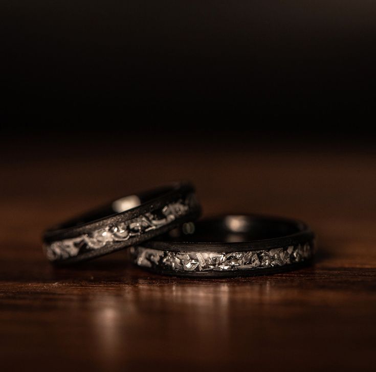 two wedding bands sitting on top of a wooden table