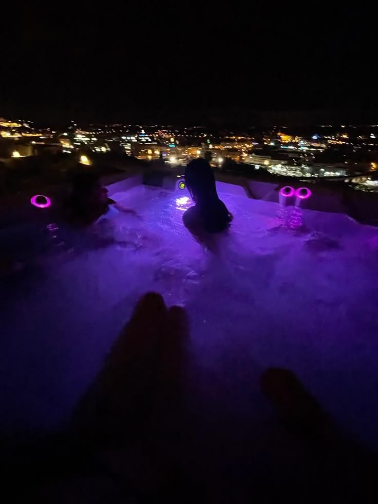 people are sitting in the snow at night with their feet up and one person standing on top