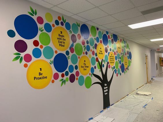 an office wall decorated with colorful circles and tree decals on the walls, along with construction tape