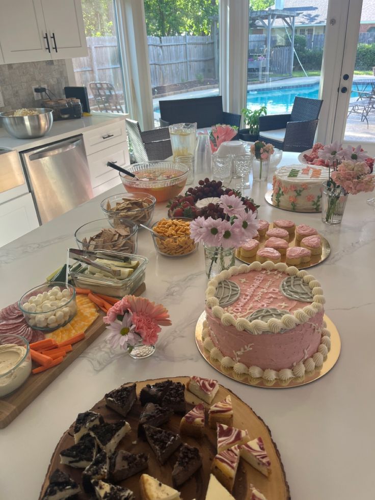 a table filled with cakes and desserts on it's side, next to a pool