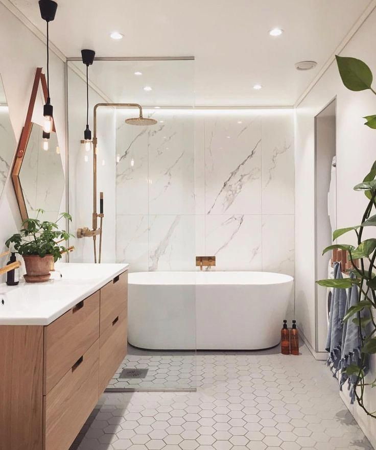 a white bath tub sitting next to a wooden cabinet in a bathroom under a mirror