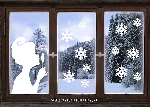 a window with snowflakes on it and a person looking out at the trees outside