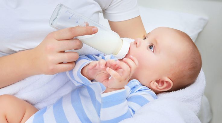 a woman feeding a baby with a bottle