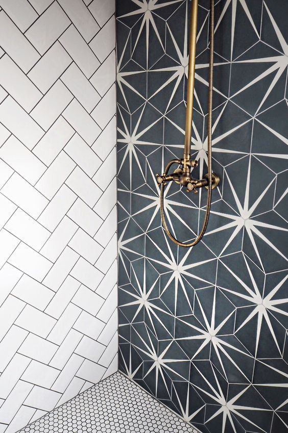 a bathroom with black and white tiles on the wall, shower head and hand held faucet