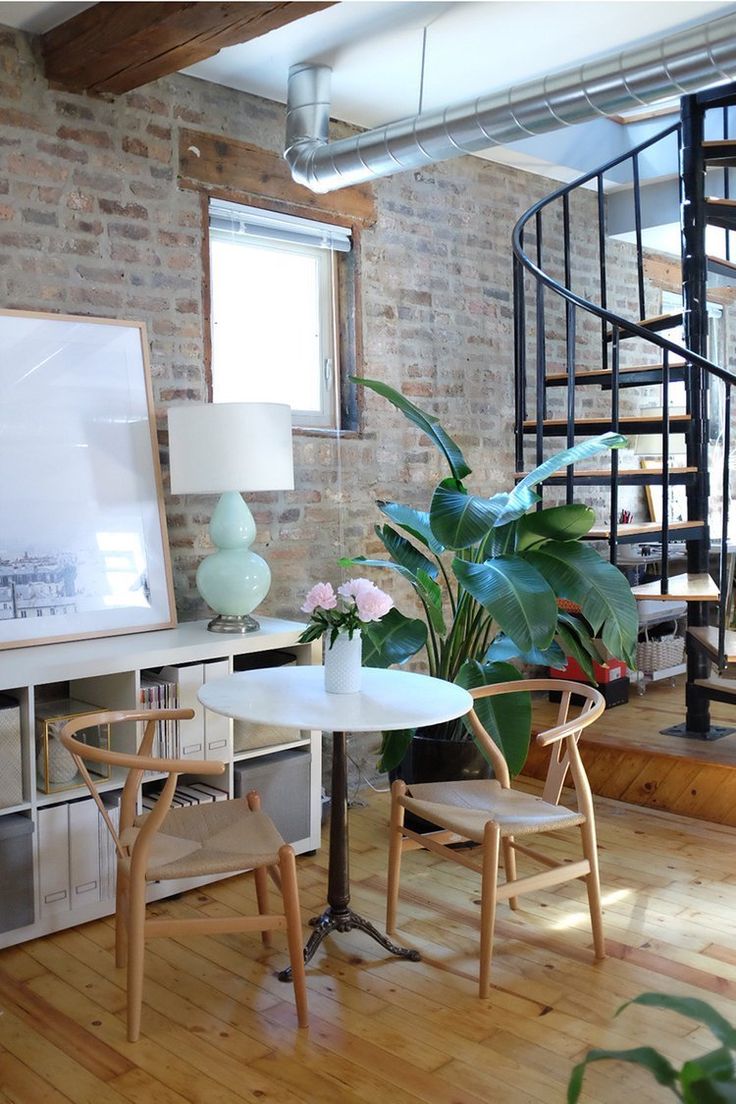 a living room with a spiral staircase next to a table and two chairs in front of it