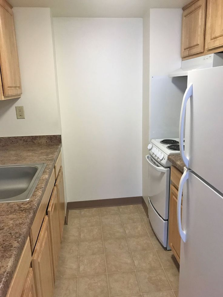 an empty kitchen with white appliances and wood cabinets