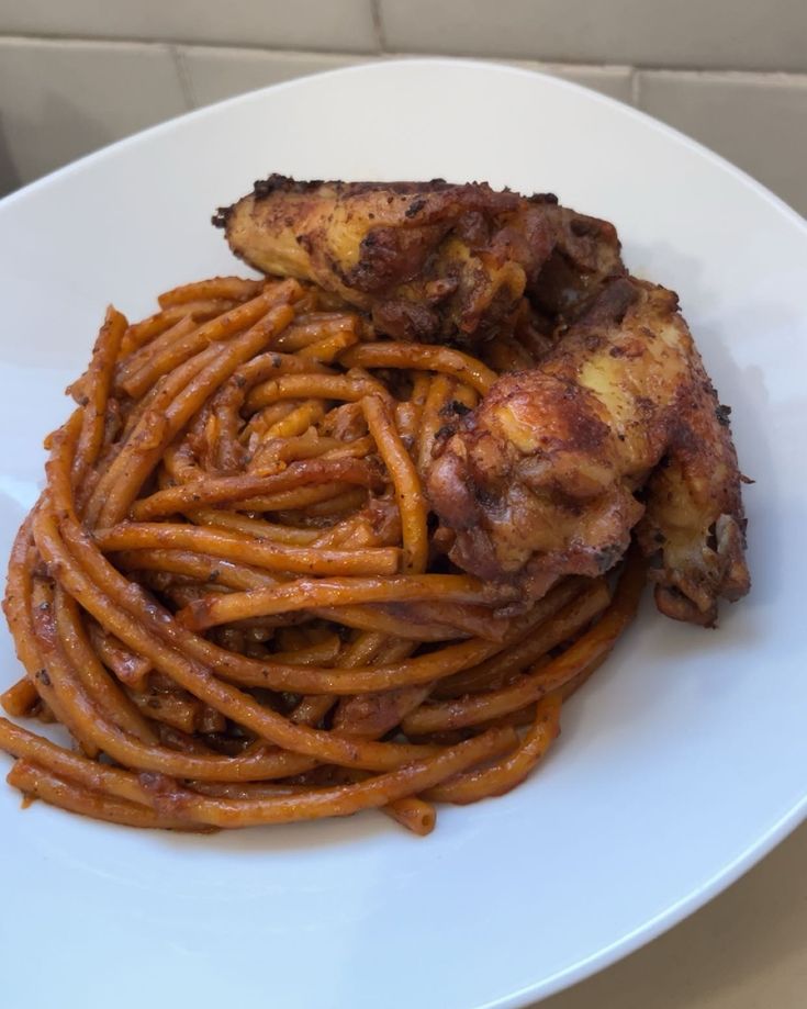 a white plate topped with chicken wings and spaghetti