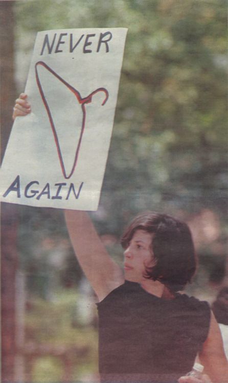 a woman holding up a sign that says never again