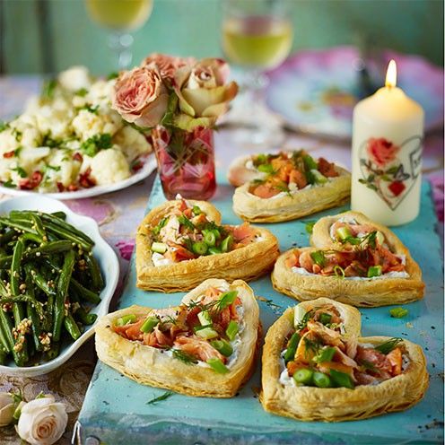 many small pastries are arranged on a table with flowers and other foods in the background