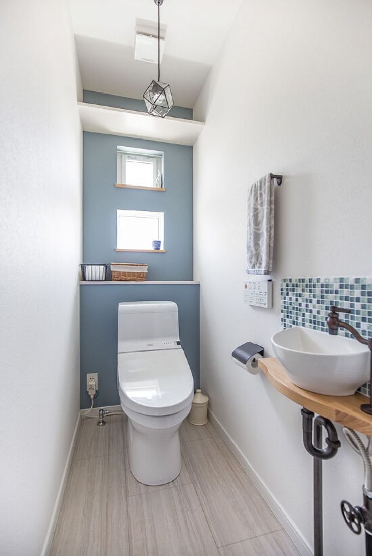 a white toilet sitting next to a sink in a bathroom under a window above a mirror