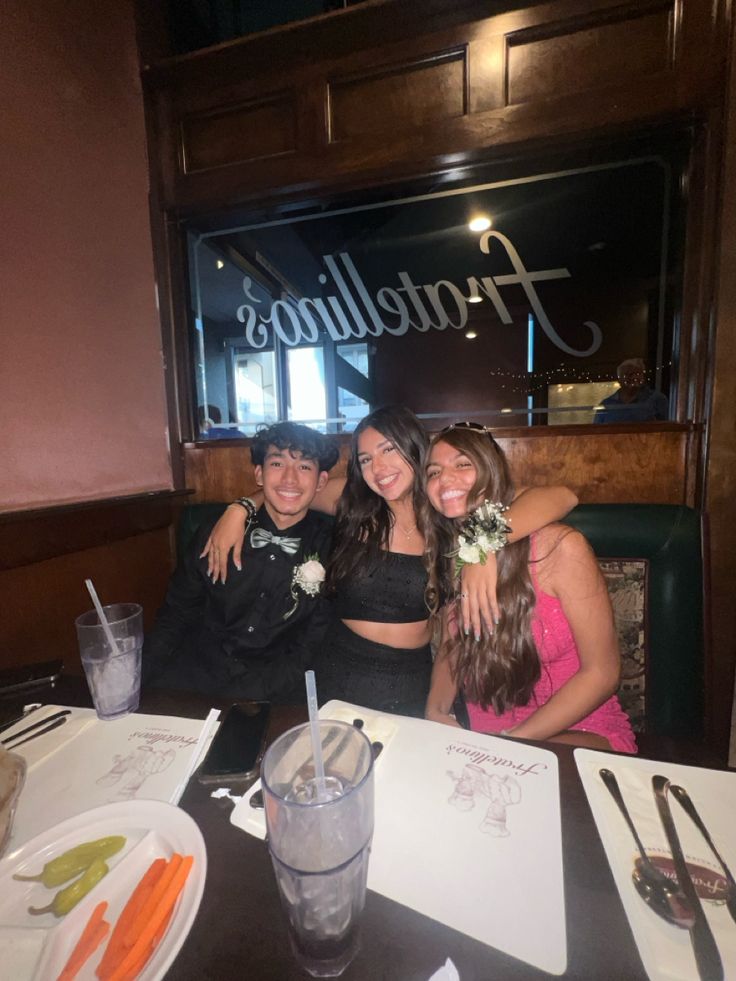 three people sitting at a table in front of a sign that says frootelinos