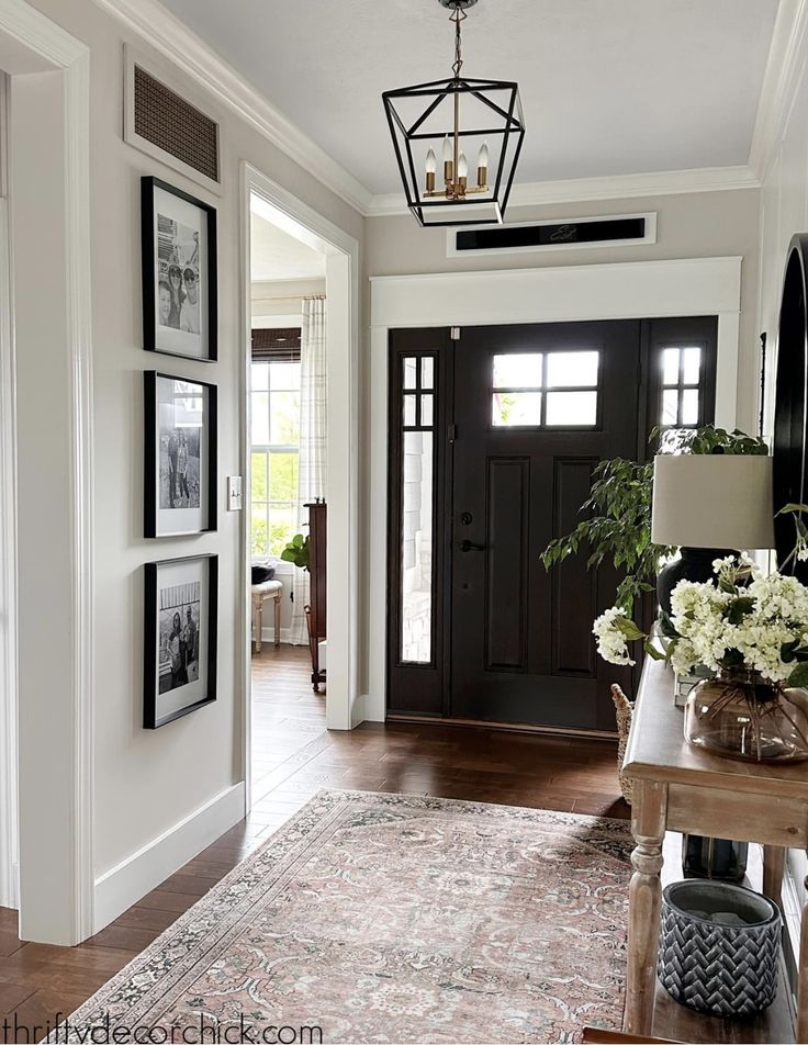 an entryway with pictures on the wall and a rug in front of the door