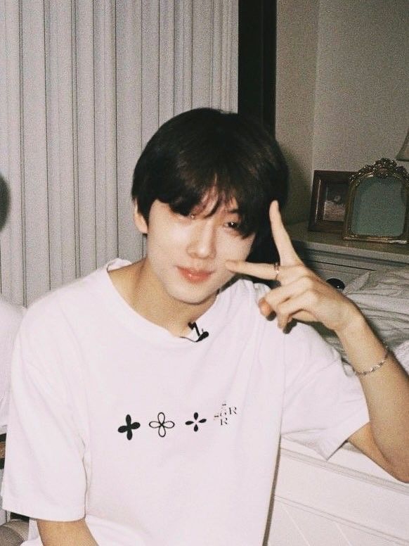 a young man sitting on top of a bed making the peace sign with his fingers