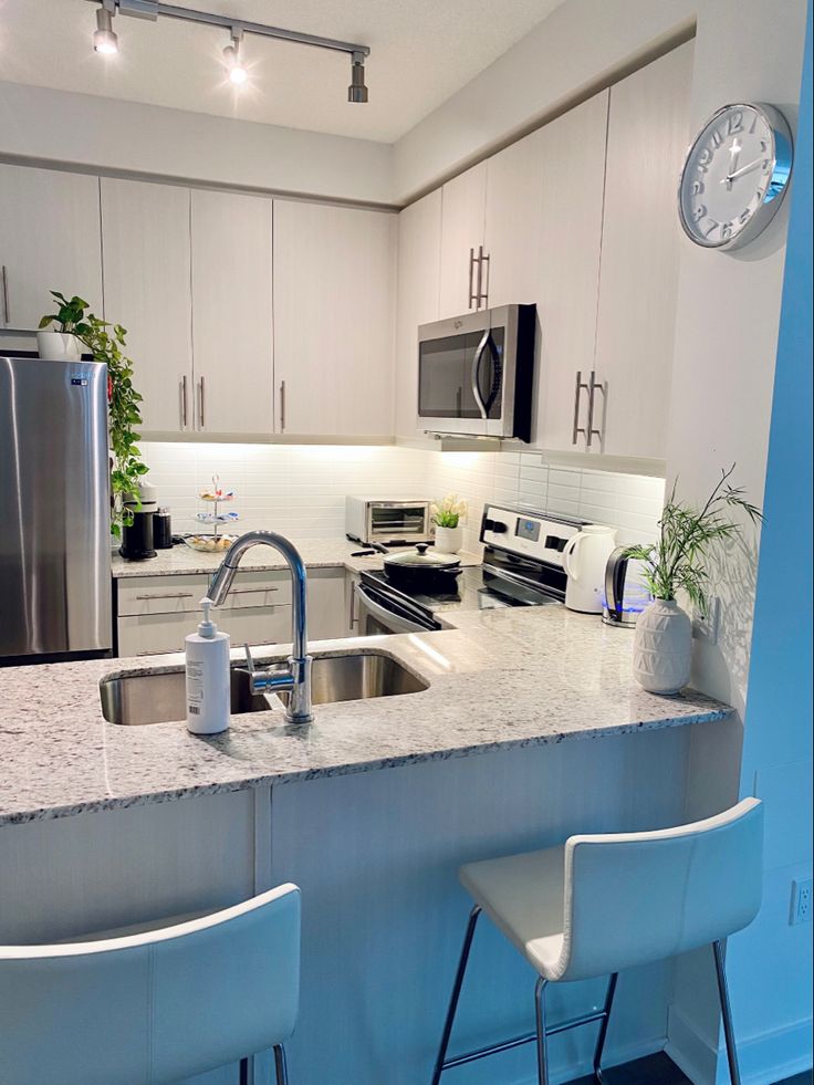 a kitchen with two stools next to a counter top and a clock on the wall