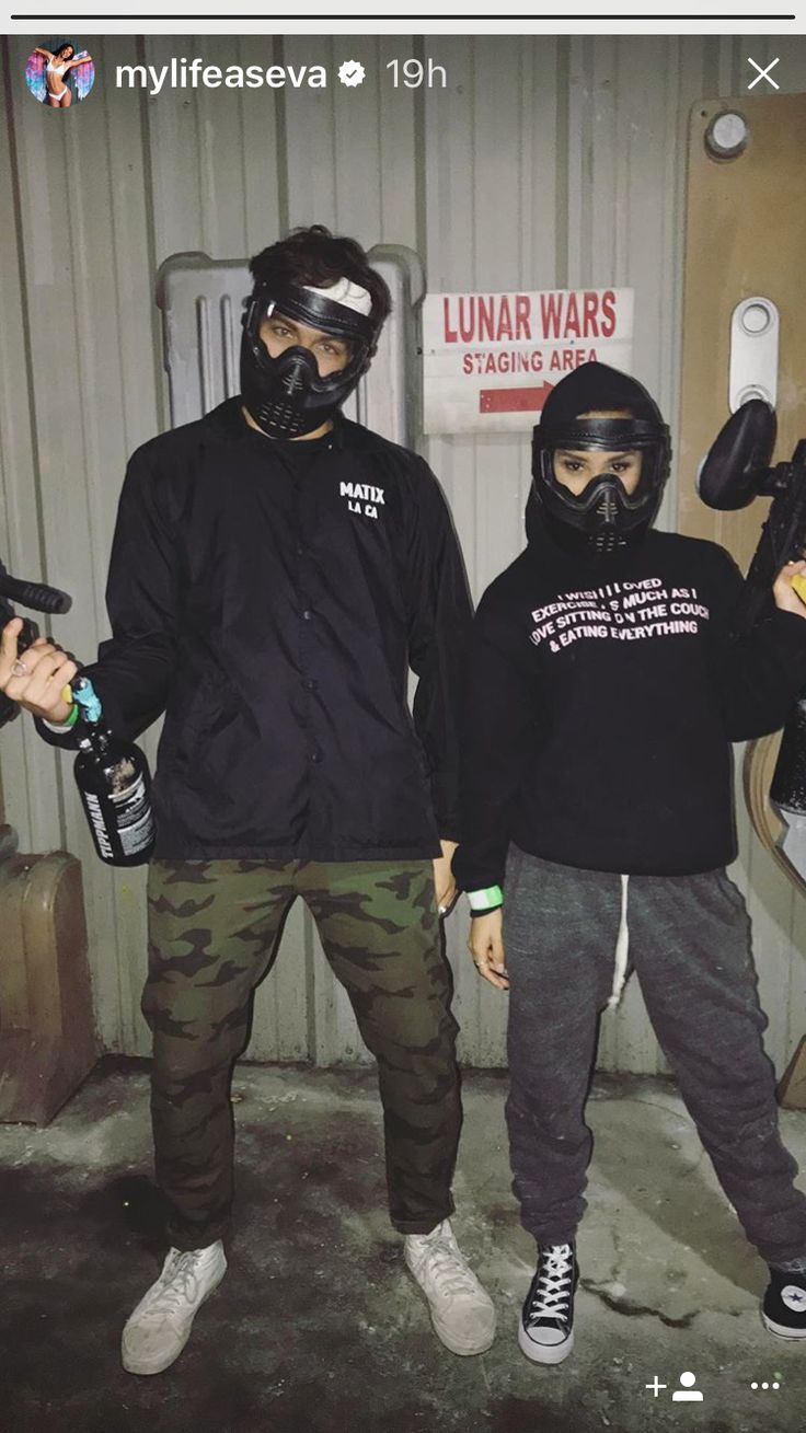 two people in black jackets and gas masks standing next to each other with their hands on their hips