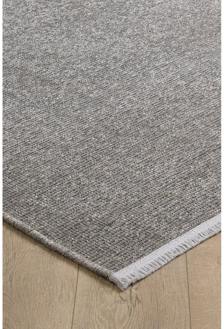 an area rug with grey and white stripes on the bottom, in front of a wooden floor