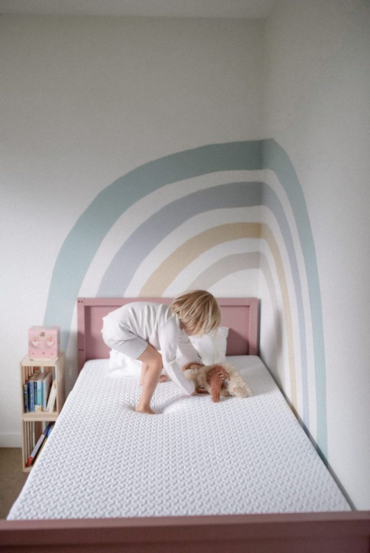 a small child is playing with a dog on a bed in a room that has striped walls