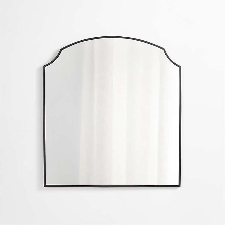 a mirror that is on the wall in front of a white wall with a black frame