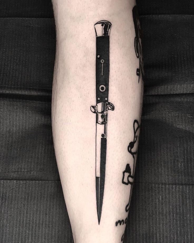 a person with a knife tattoo on their leg