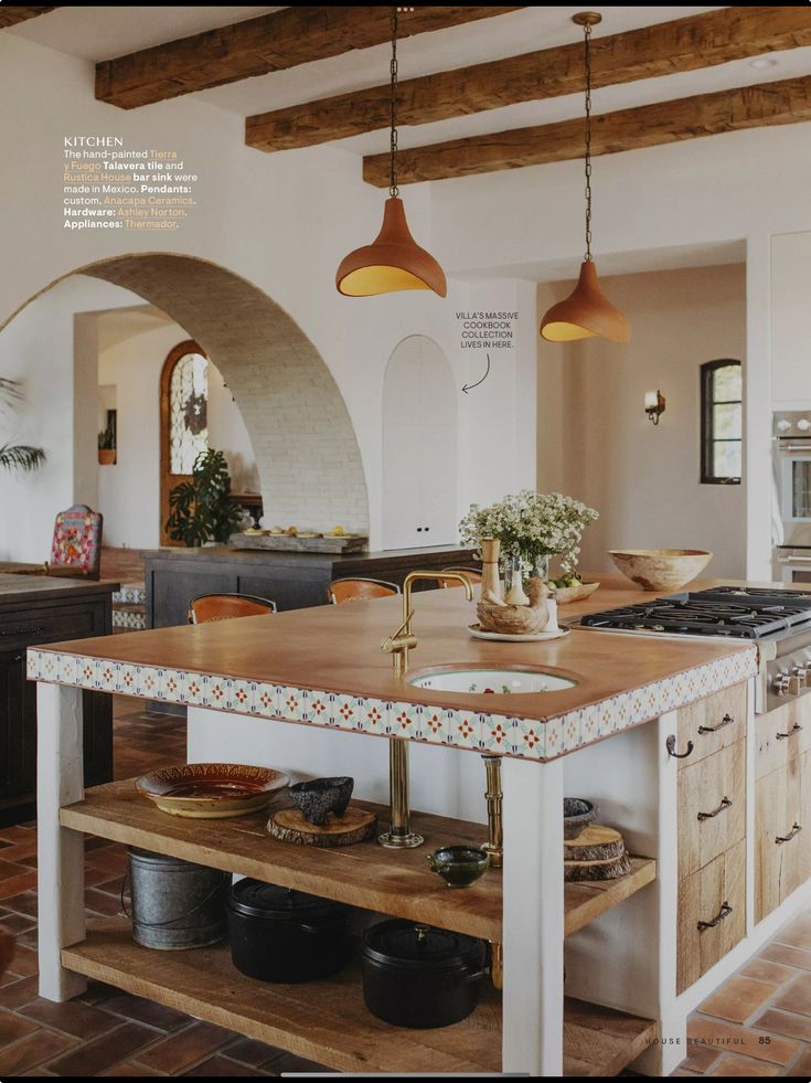 a kitchen with an island in the middle and two lights hanging from it's ceiling