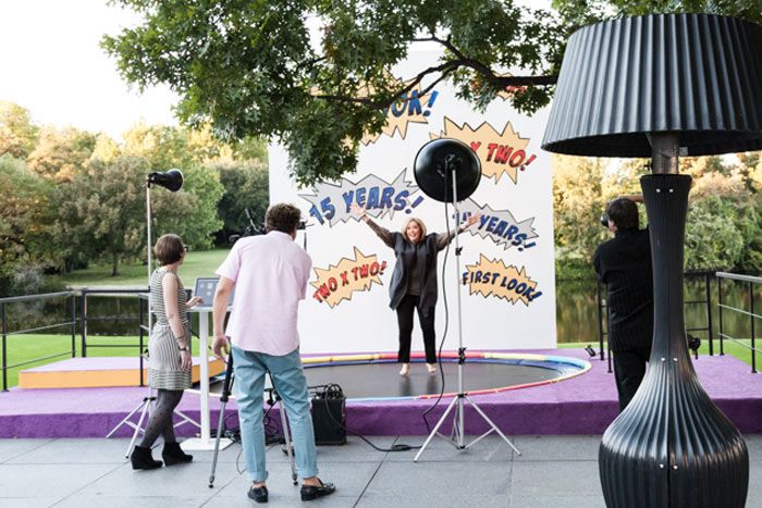 three people standing on a stage with microphones in front of them and an advertisement behind them