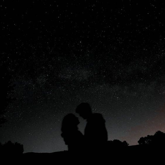 two people are standing under the stars in the night sky