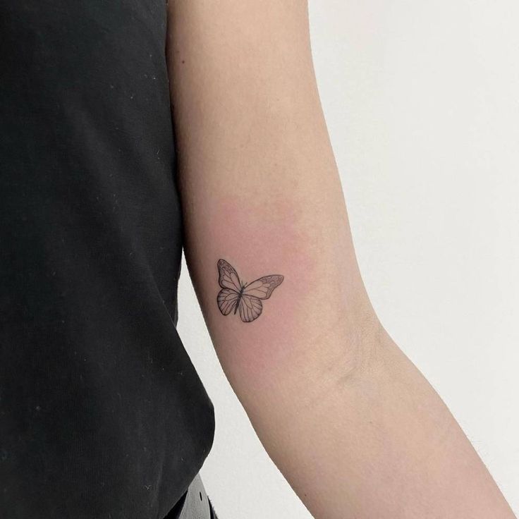 a woman's arm with a small butterfly tattoo on the left side of her arm