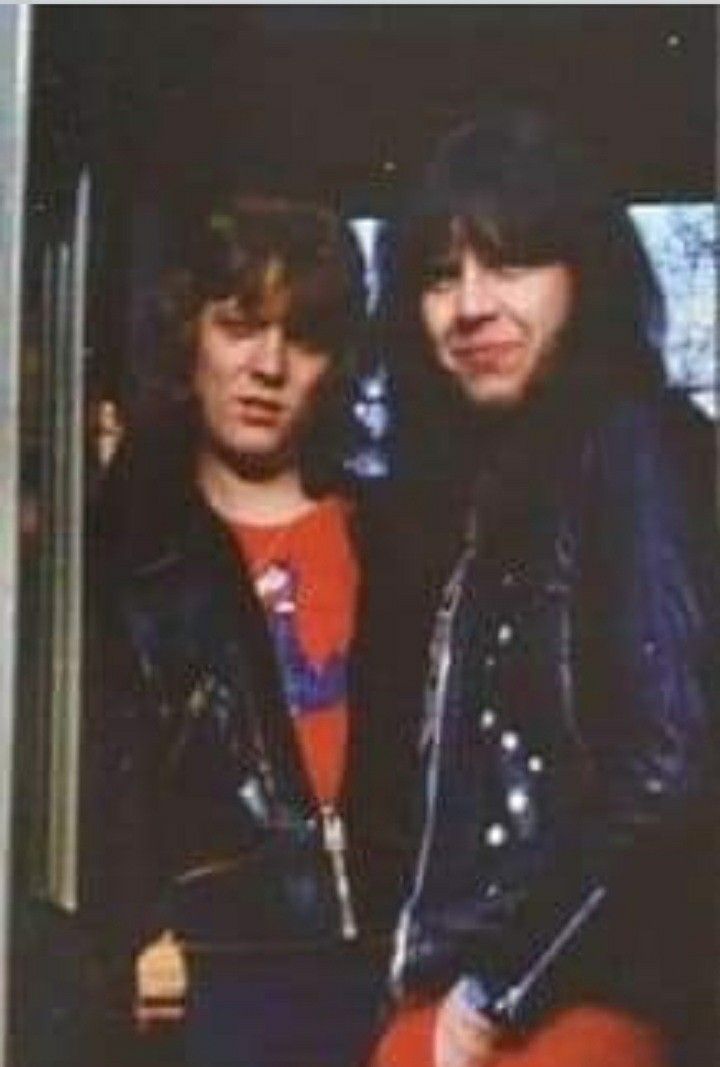 two young men standing next to each other in front of a door with their arms around one another