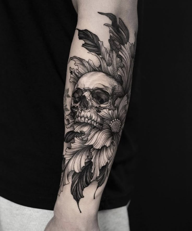 a man's arm with a skull and feathers on it