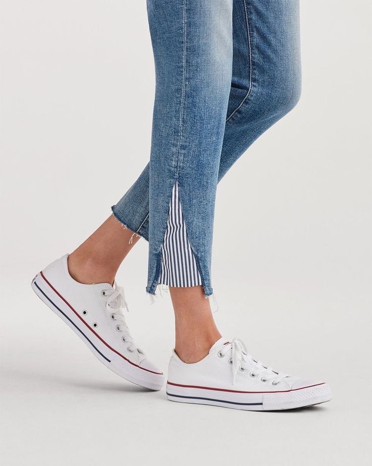 a woman's legs in ripped jeans and white sneakers