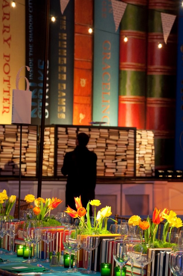 an image of a table with vases and flowers on it in front of bookshelves