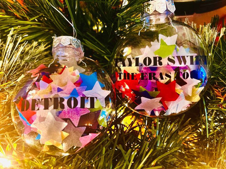 two christmas ornaments that say taylor swift and the stars to them are hanging from a tree