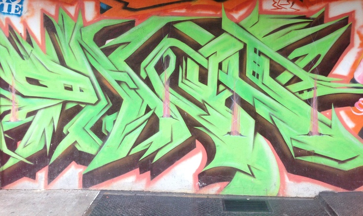 graffiti on the side of a building with green and black letters that spell it out