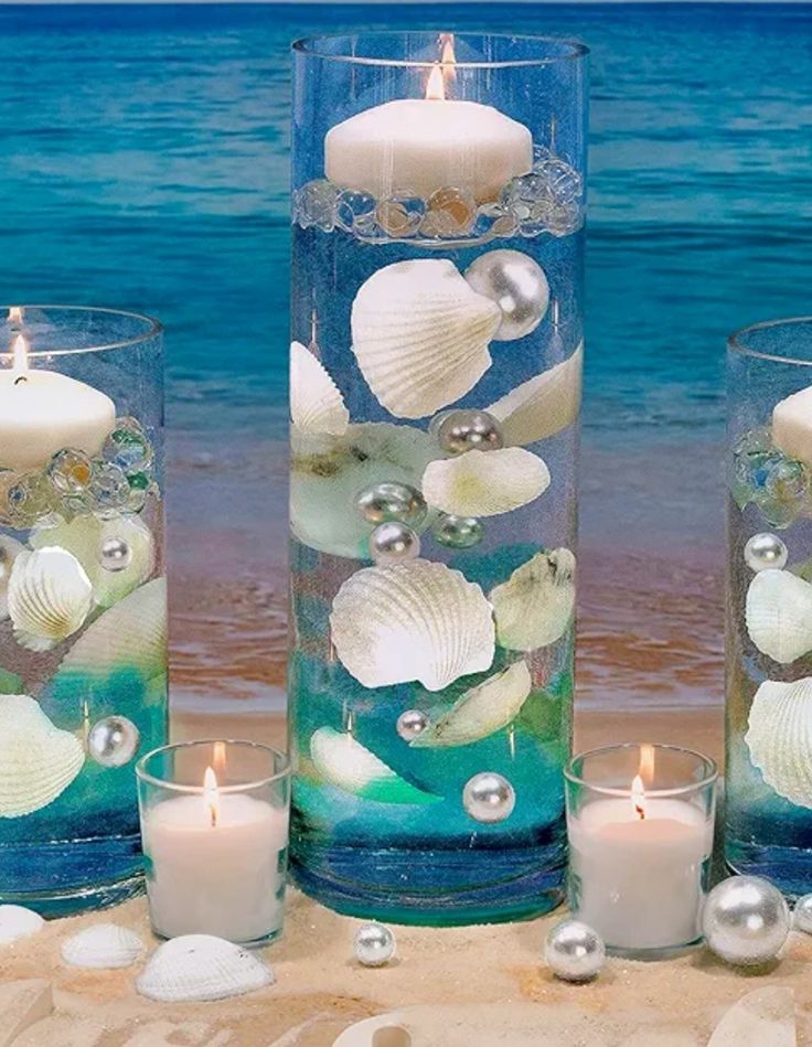 seashells and pearls are arranged in glass vases on the beach