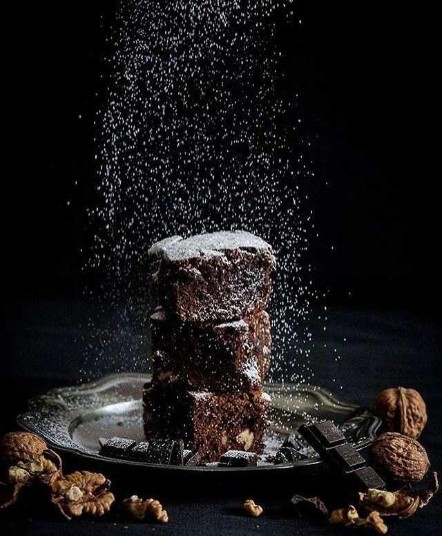 a stack of brownies sitting on top of a plate covered in powdered sugar