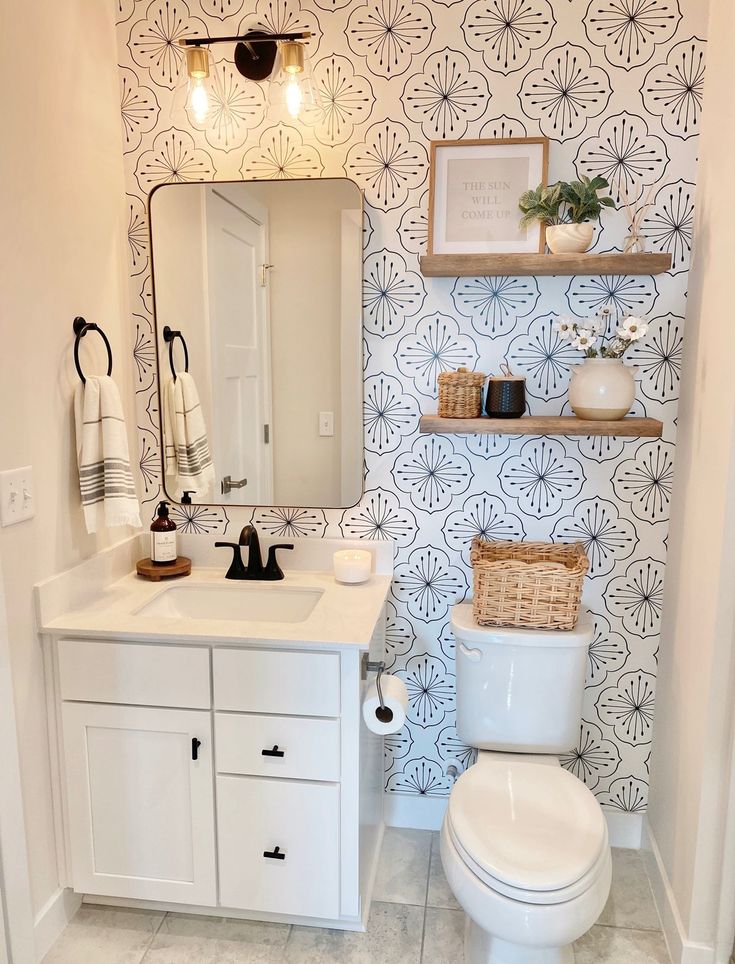 a white toilet sitting under a bathroom mirror next to a sink and shelf with baskets on it