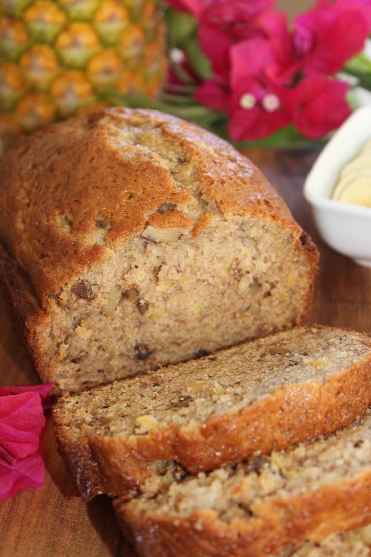 sliced loaf of banana bread with butter and flowers in the background