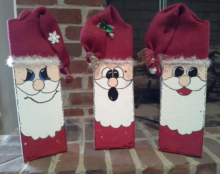 two wine bottles decorated like santa clausees on a brick fireplace mantel in front of a fire place