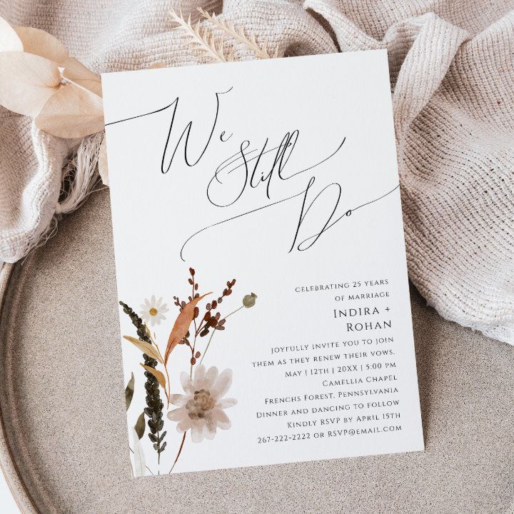 a white wedding card with flowers on it sitting on a plate next to a napkin