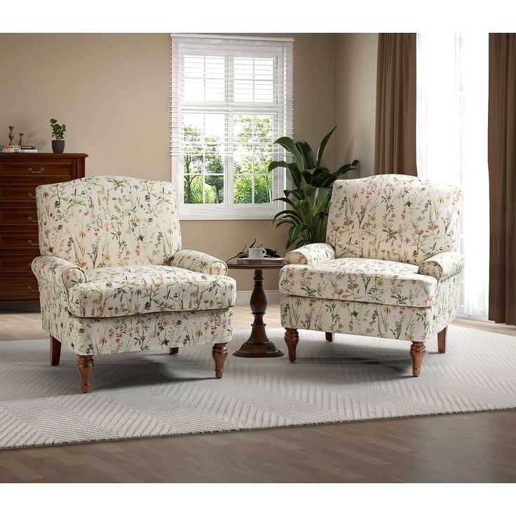 a living room with two chairs and a table in front of a window on top of a rug