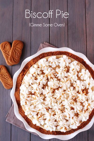 a pie sitting on top of a wooden table next to some cookies and other food