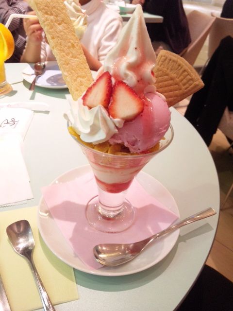 an ice cream sundae with strawberries and whipped cream in a glass dish on a table