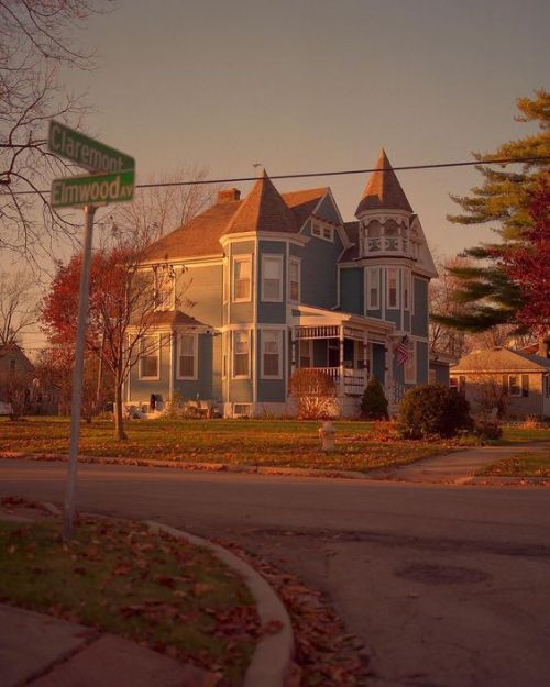 a street sign in front of a two story house on the corner of an intersection